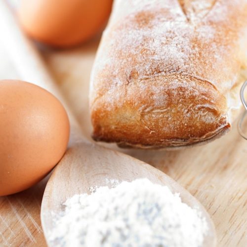 A wooden cutting board topped with bread and eggs