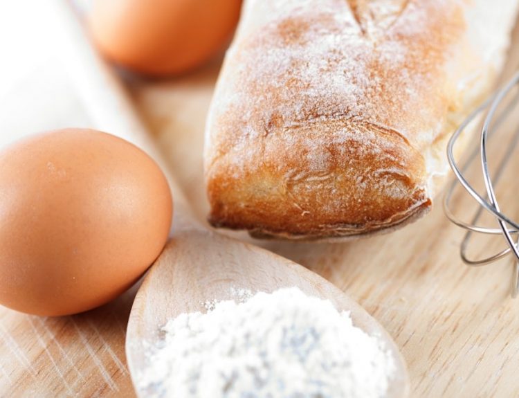 A wooden cutting board topped with bread and eggs