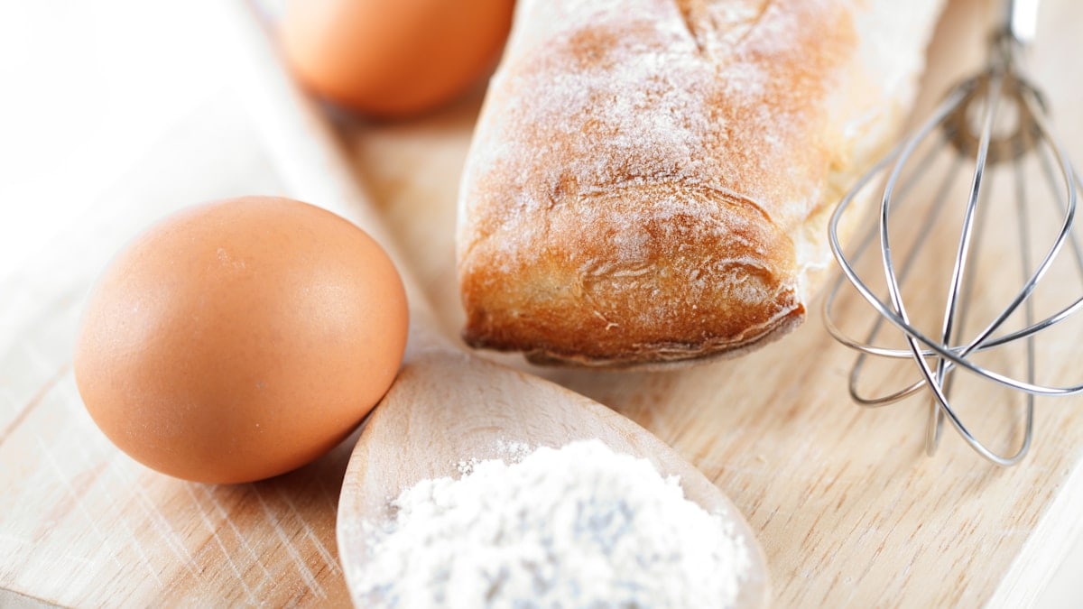A wooden cutting board topped with bread and eggs
